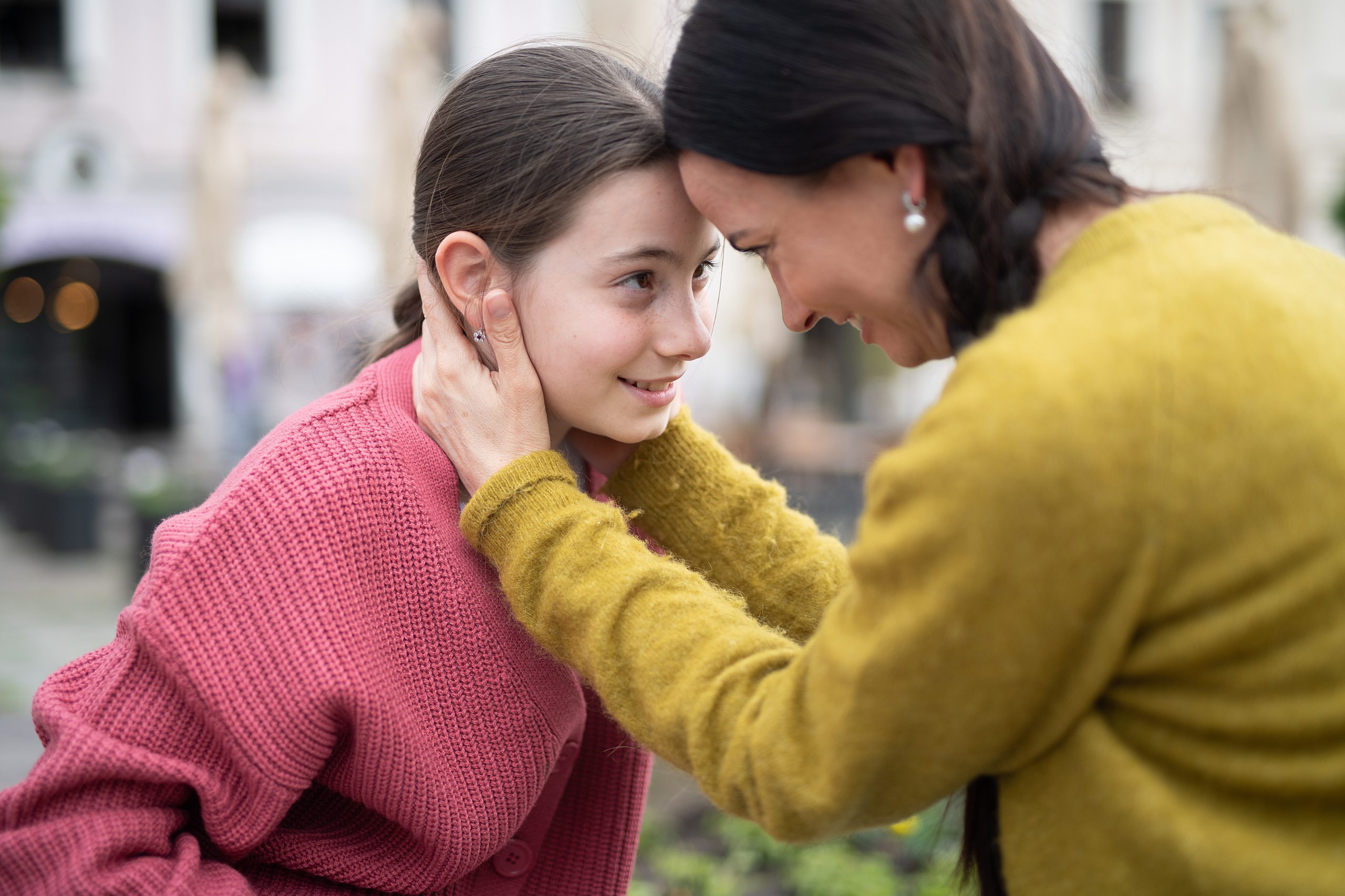 A mother leaning in close, listening to her daughter